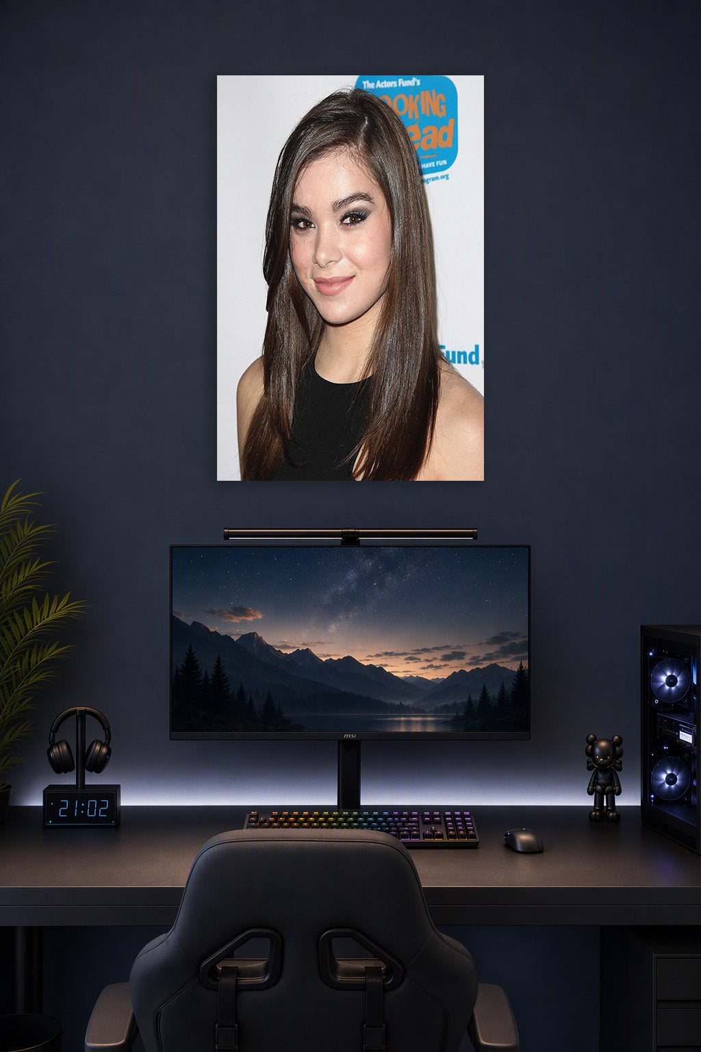 Hailee Steinfeld in a gaming desk setup above a monitor.