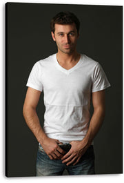 Handsome man canvas wall art print presents a full-length studio portrait of a man in a white T-shirt and jeans on a dark background.