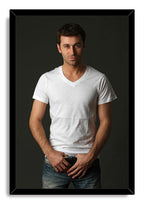Handsome man framed wall art print features a dark-haired man wearing a white V-neck shirt and blue jeans against a charcoal backdrop.