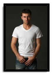 Handsome man framed wall art print features a dark-haired man wearing a white V-neck shirt and blue jeans against a charcoal backdrop.