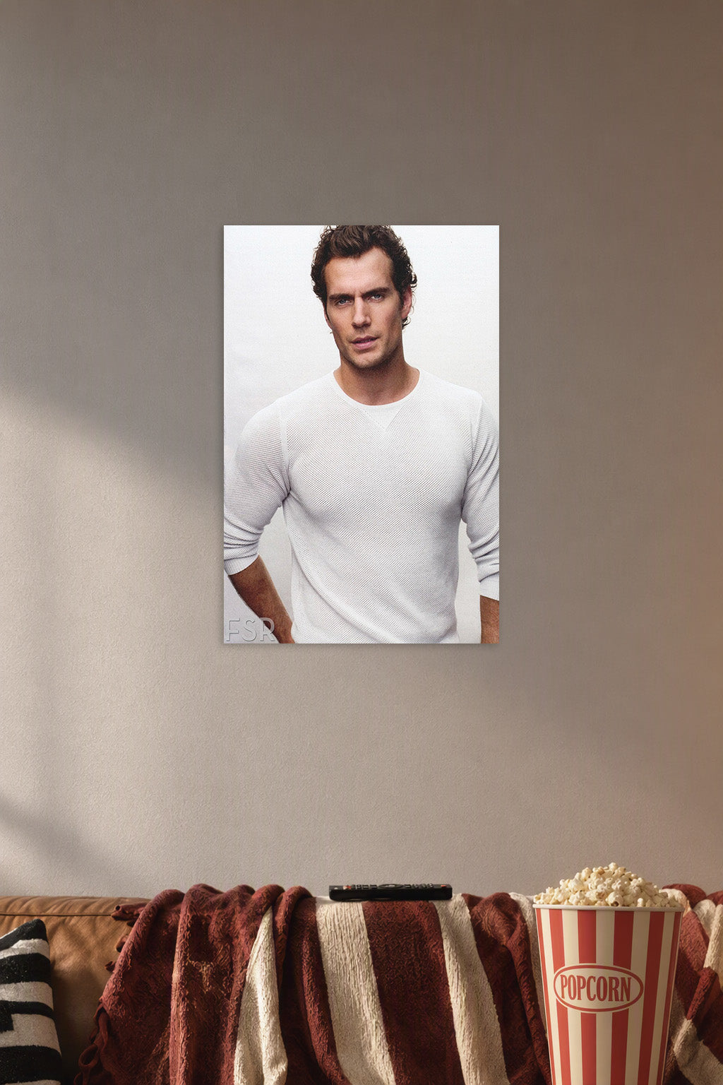 Henry Cavill in a cozy movie room above a brown sofa with popcorn.