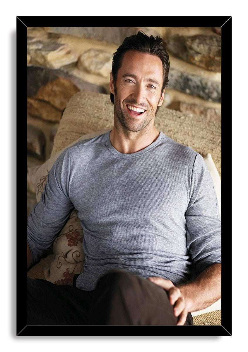 Hugh Jackman framed wall art print featuring the smiling actor seated on a sofa in gray, set in a black mitered frame.