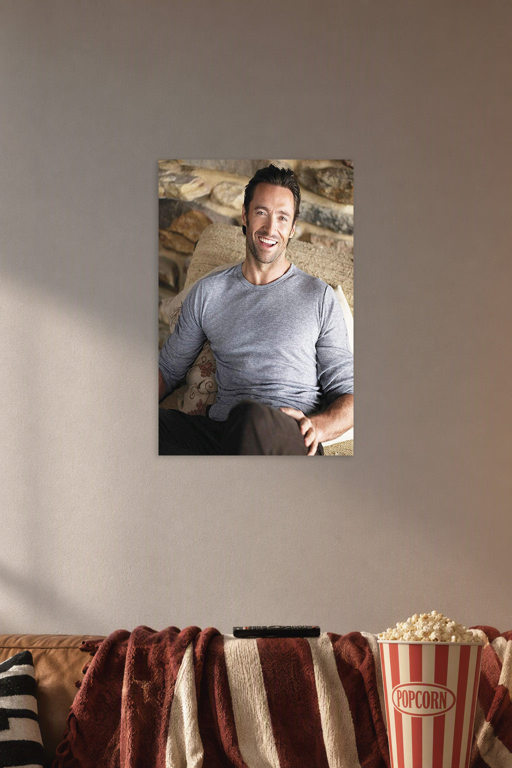 Hugh Jackman in a cozy movie room above a brown sofa with popcorn.