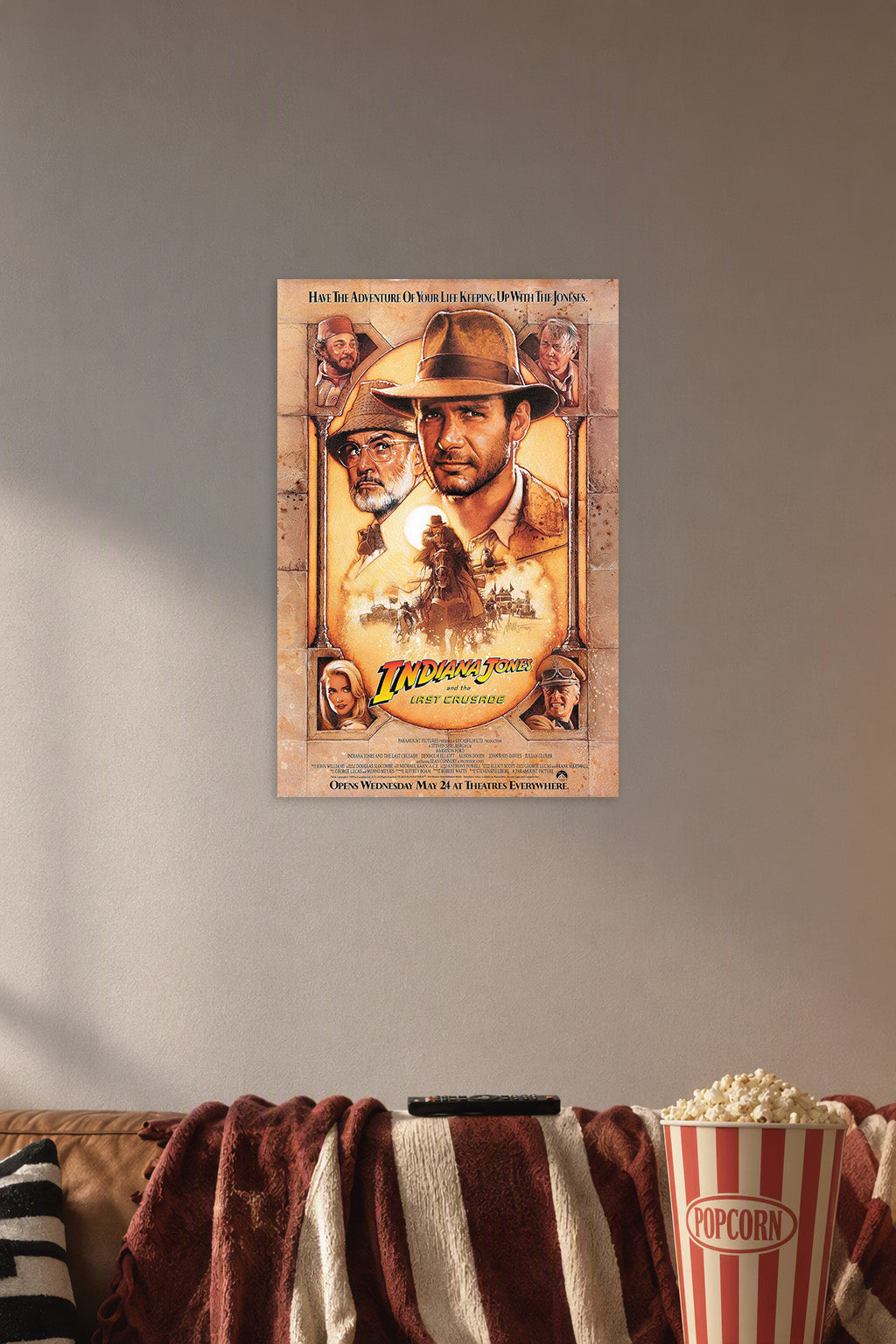 Indiana Jones and the Last Crusade Movie Poster in a cozy movie room above a brown sofa with popcorn.
