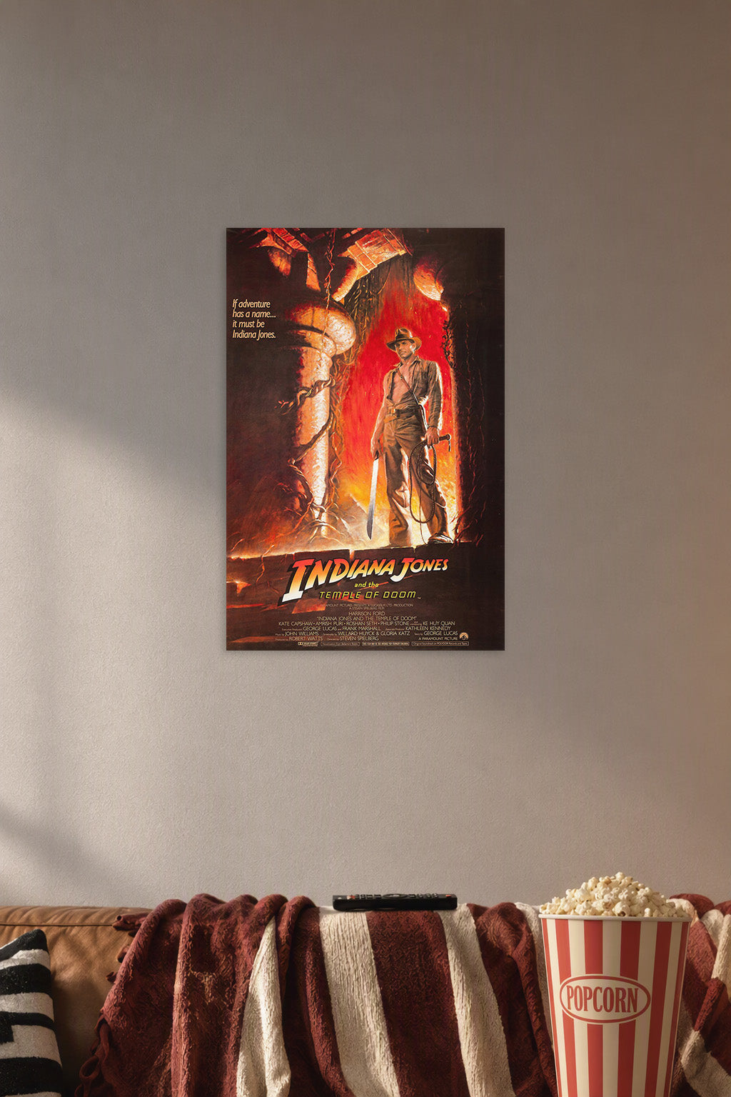Indiana Jones and the Temple of Doom in a cozy movie room above a brown sofa with popcorn.