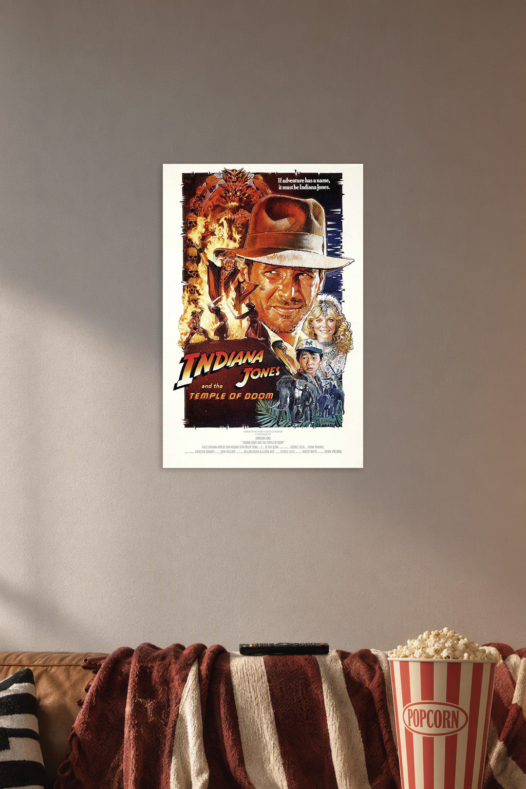 Indiana Jones and the Temple of Doom Movie Poster in a cozy movie room above a brown sofa with popcorn.