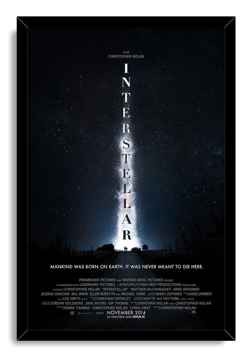 Interstellar framed wall art print displays a starry blue-black sky, bright central nebula, vertical title, and figures on a road.
