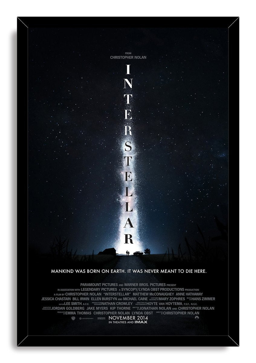 Interstellar framed wall art print displays a starry blue-black sky, bright central nebula, vertical title, and figures on a road.