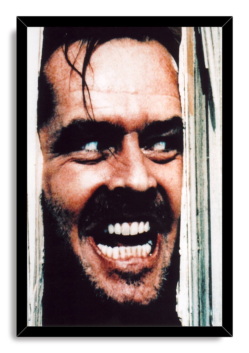 Jack Torrance framed wall art print displays his intense grimacing face through broken white wood in a black frame.