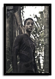 After Earth framed wall art print of Jaden Smith wearing an advanced dark bodysuit in a shadowy forest, set in a black frame.