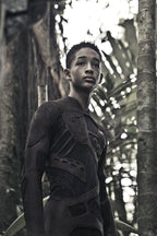 After Earth poster art of Jaden Smith as Cypher Raige in a dark textured survival suit amid tall jungle trees.