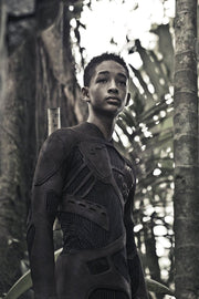 After Earth poster art of Jaden Smith as Cypher Raige in a dark textured survival suit amid tall jungle trees.