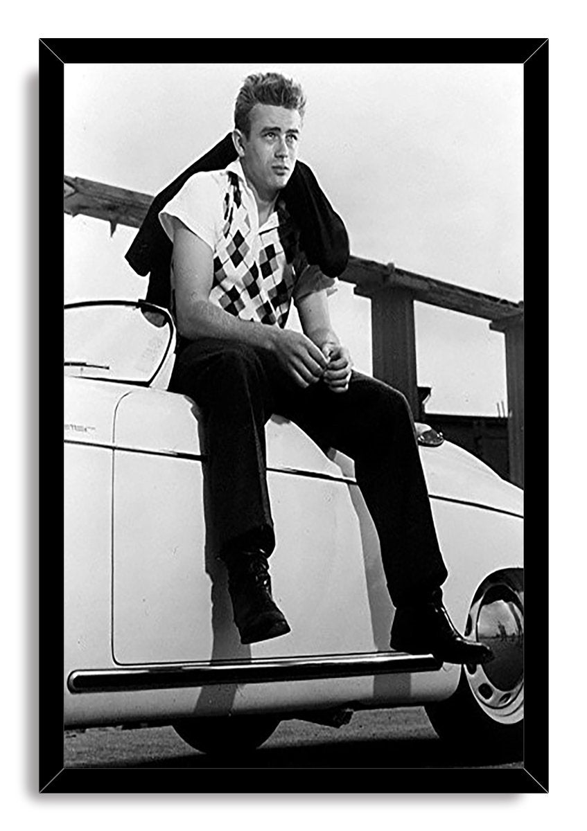 James Dean framed wall art print presents a black-and-white photo of the actor perched on a classic white car, bordered by a black frame.