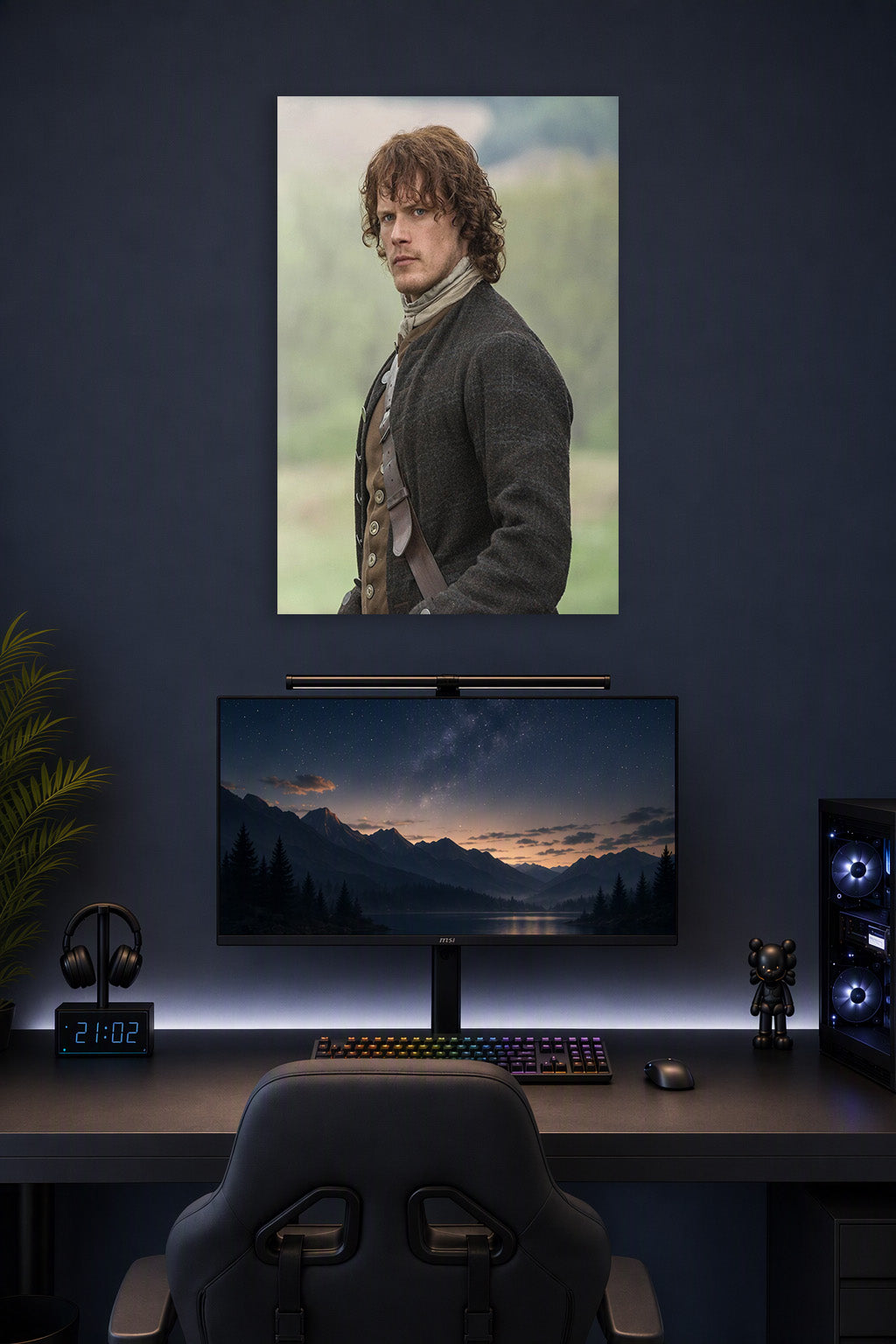 Jamie Fraser (Sam Heughan) from Outlander in a gaming desk setup above a monitor.