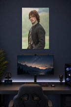 Jamie Fraser (Sam Heughan) from Outlander in a gaming desk setup above a monitor.