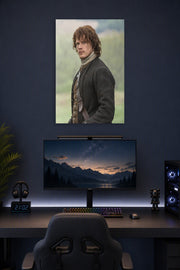 Jamie Fraser (Sam Heughan) from Outlander in a gaming desk setup above a monitor.