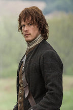 Jamie Fraser poster features a close portrait of Sam Heughan in a dark coat, brown waistcoat, scarf, and leather strap against a soft green landscape.