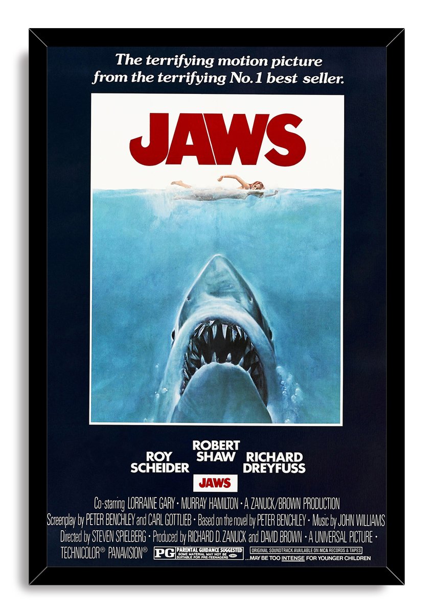 Jaws movie poster framed wall art with a black mitered frame, red title, swimmer, and great white shark beneath blue water.