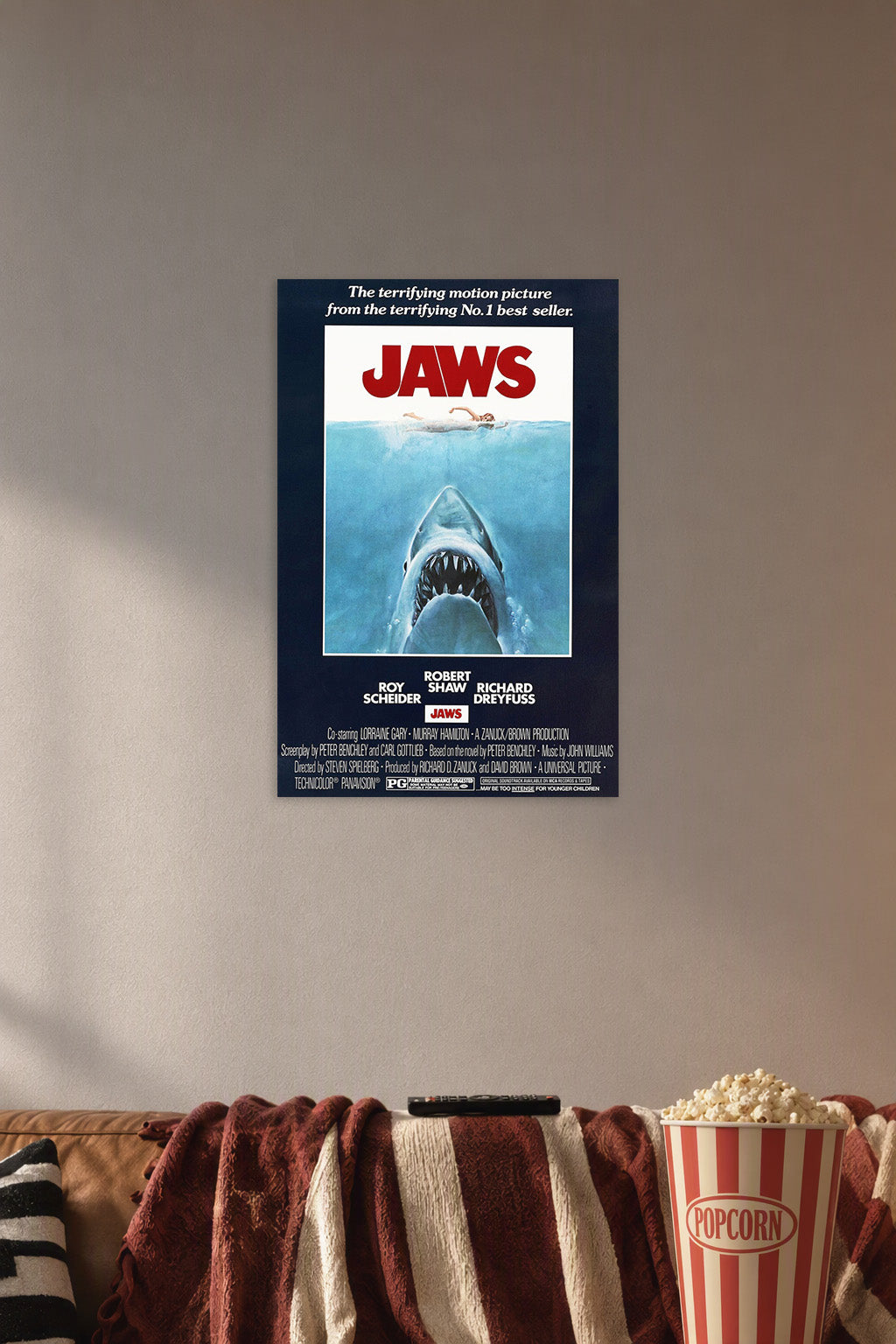 Jaws Movie Poster in a cozy movie room above a brown sofa with popcorn.