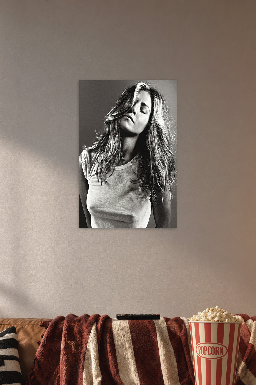 Jennifer Aniston in a cozy movie room above a brown sofa with popcorn.