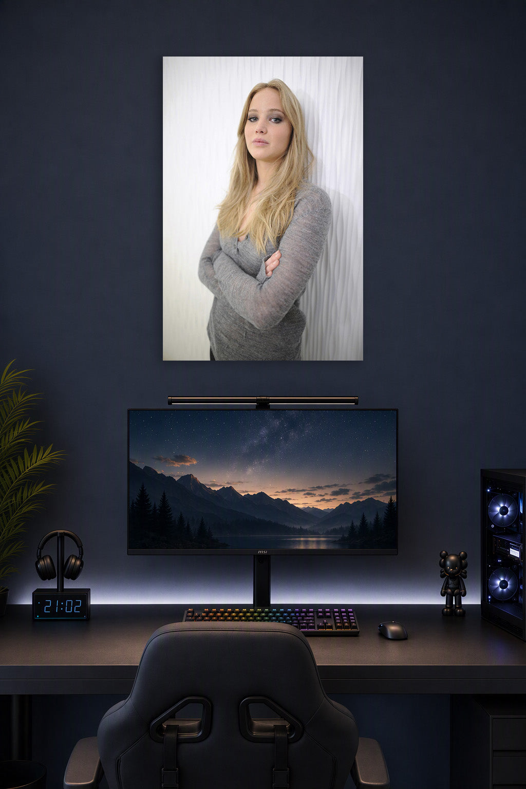Jennifer Lawrence in a gaming desk setup above a monitor.