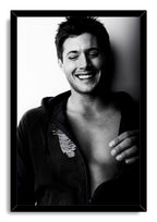 Jensen Ackles framed wall art print displays a black-and-white laughing portrait in a glossy black rectangular frame.