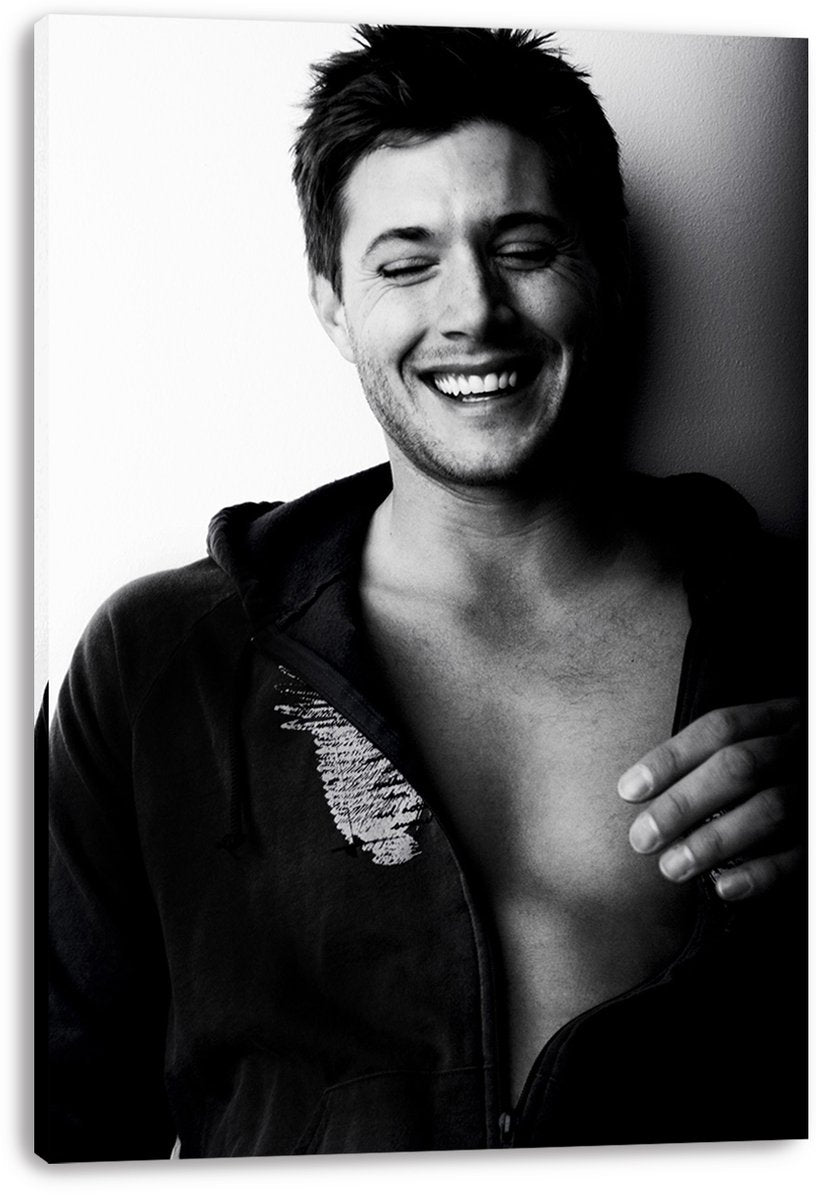 Jensen Ackles canvas wall art print presents a monochrome laughing portrait, with his open hoodie and hand across his chest.