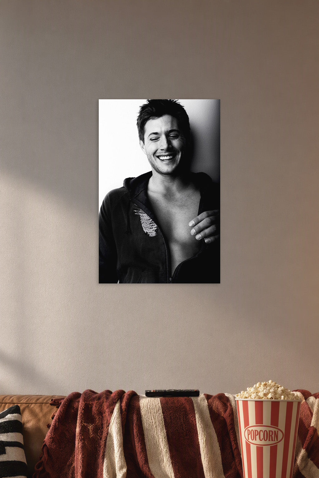 Jensen Ackles Laughing in a cozy movie room above a brown sofa with popcorn.