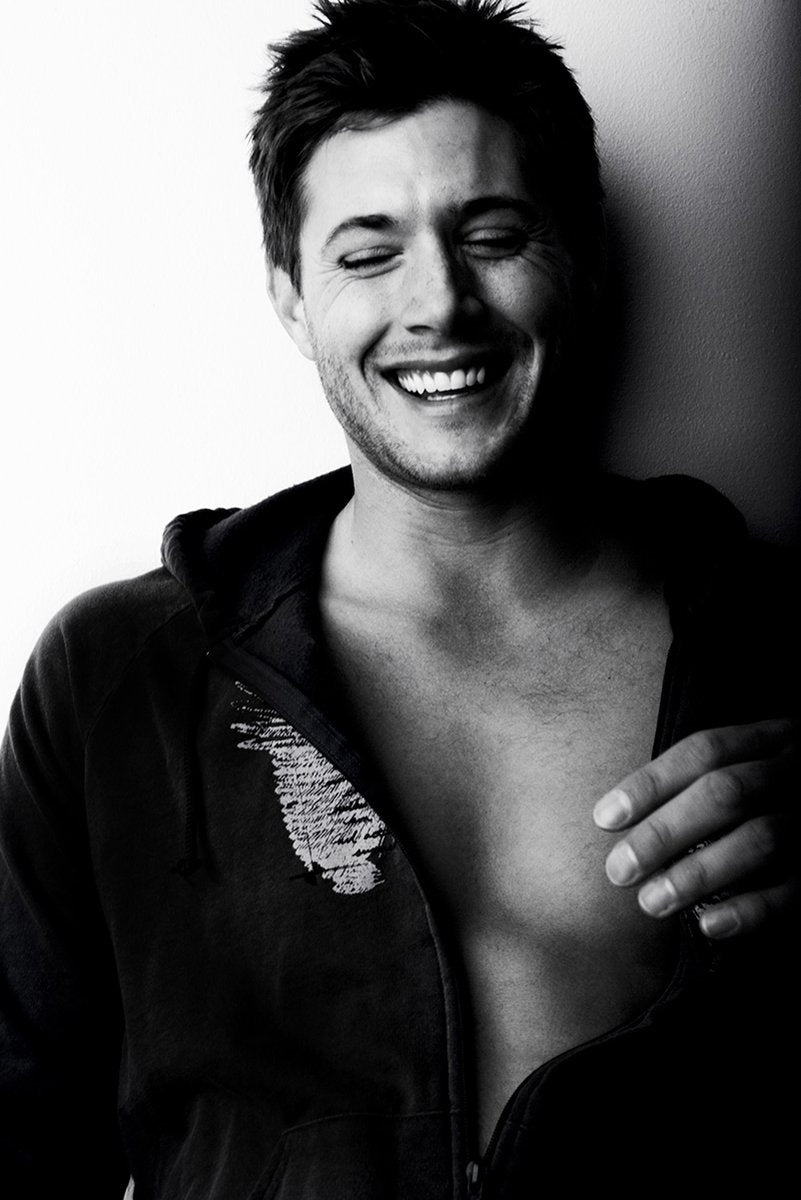 Jensen Ackles poster features a black-and-white portrait of him laughing with closed eyes in an open dark hoodie.