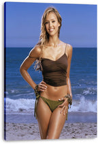 Jessica Alba canvas wall art print displays her smiling in beachwear before blue ocean waves, with the canvas edges visibly wrapped.