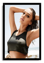 Jessica Alba framed wall art print portraying her with raised arms and wet hair in a black crop top by the sea.