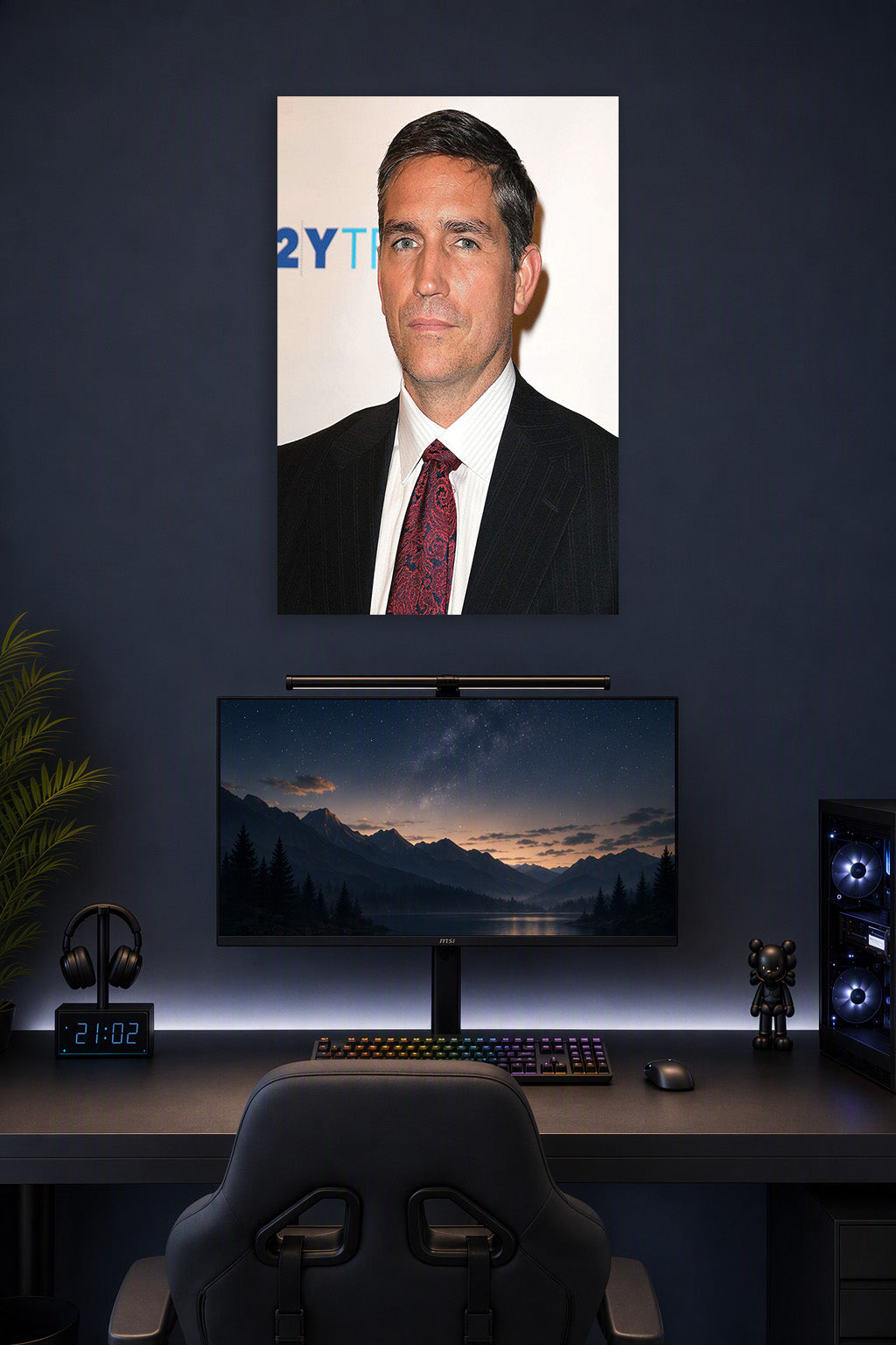 Jim Caviezel in a gaming desk setup above a monitor.