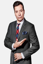 Jimmy Fallon poster portrait in a gray suit, plaid red and blue tie, and navy pocket square against white.