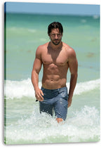 Joe Manganiello canvas wall art print features a shirtless man in blue shorts striding from pale turquoise surf.