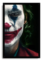 Joker framed wall art print displays a half-face clown portrait with white makeup, a red nose and smile, blue eyeshadow, and green hair.