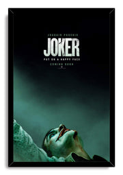 Joker framed wall art print features a black frame around Joaquin Phoenix in makeup against a shadowy teal backdrop.