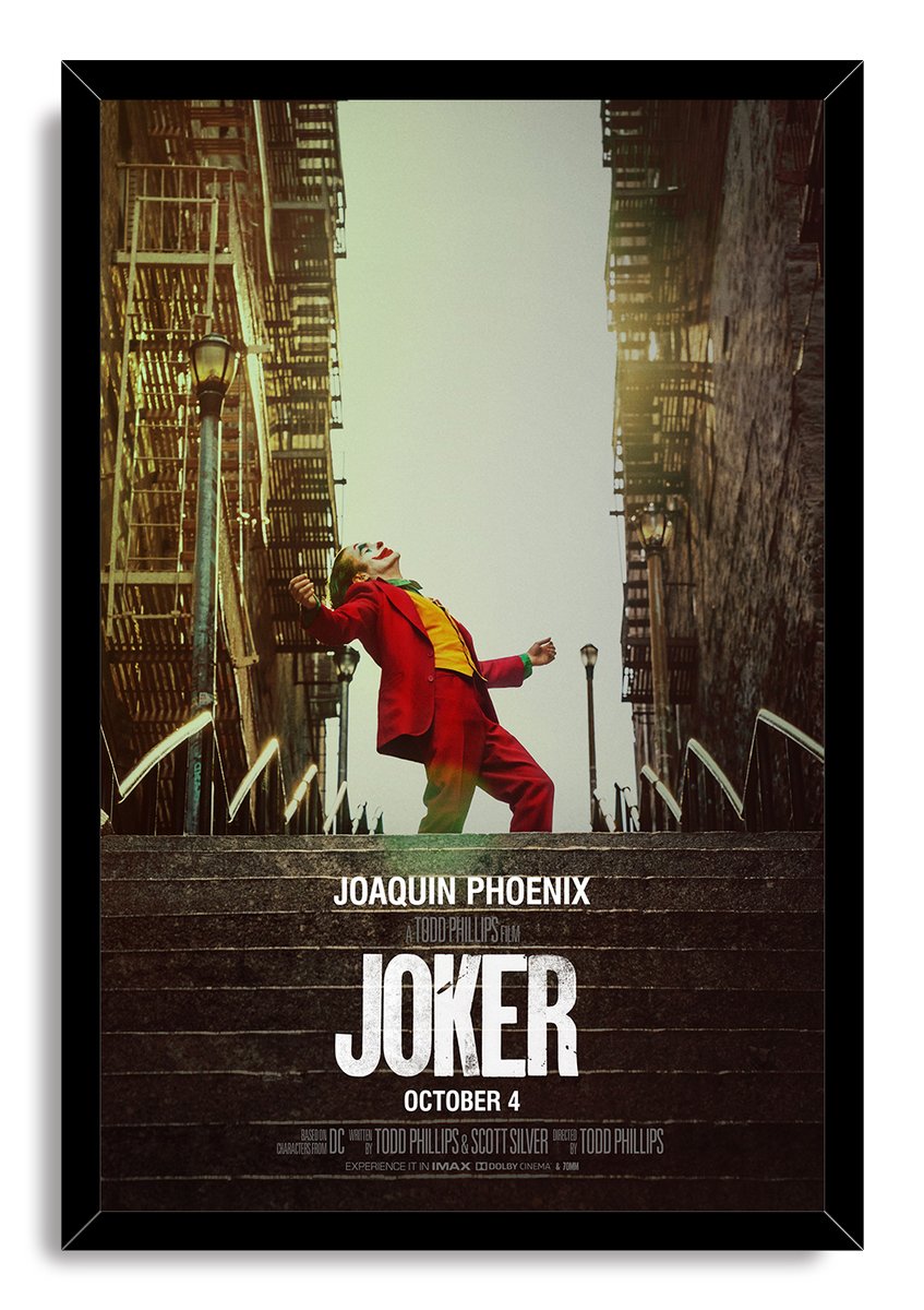 Joker framed wall art print portrays Joaquin Phoenix in clown makeup and red clothing dancing between tall city buildings.