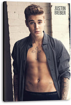Justin Bieber canvas wall art print presents the singer in an open black patterned shirt against a pale brick wall.