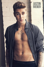 Justin Bieber poster features a close portrait of the singer in an open patterned shirt before a white brick wall.