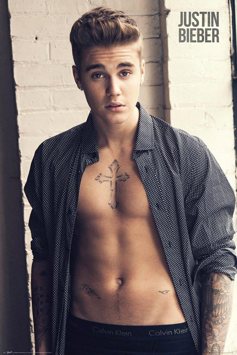 Justin Bieber poster features a close portrait of the singer in an open patterned shirt before a white brick wall.