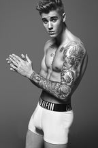 Justin Bieber poster features a black-and-white full-body portrait with clasped hands, tattoos, and white boxer briefs.