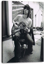 Keith Richards canvas wall art print presents a black-and-white studio portrait of the guitarist seated with an electric guitar.