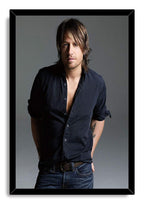 Keith Urban framed wall art print displays a studio portrait in a black frame, with dark shirt, jeans, and gray backdrop.
