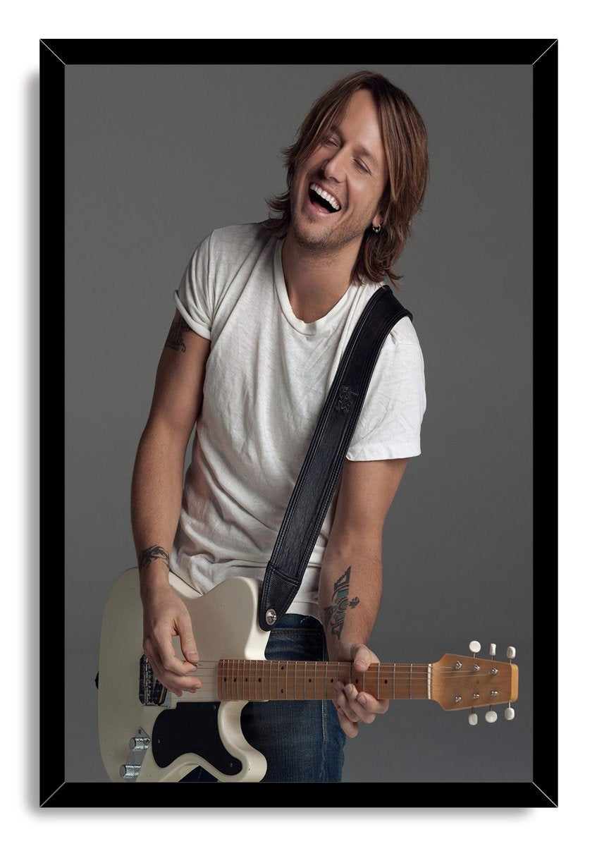 Keith Urban framed wall art print depicts the joyful musician playing a cream electric guitar, set in a glossy black frame.