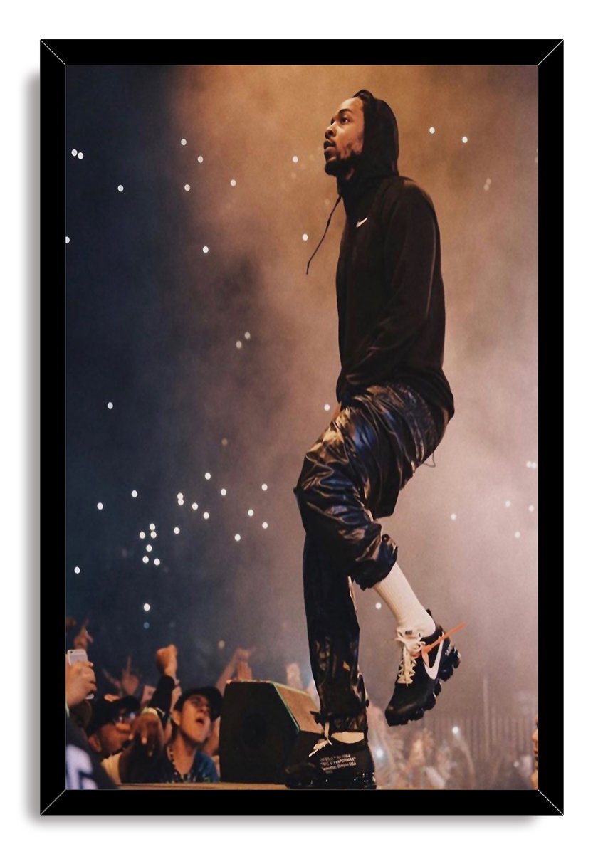 Kendrick Lamar framed wall art print features the rapper performing in a black hoodie, with raised audience hands and glowing lights below.