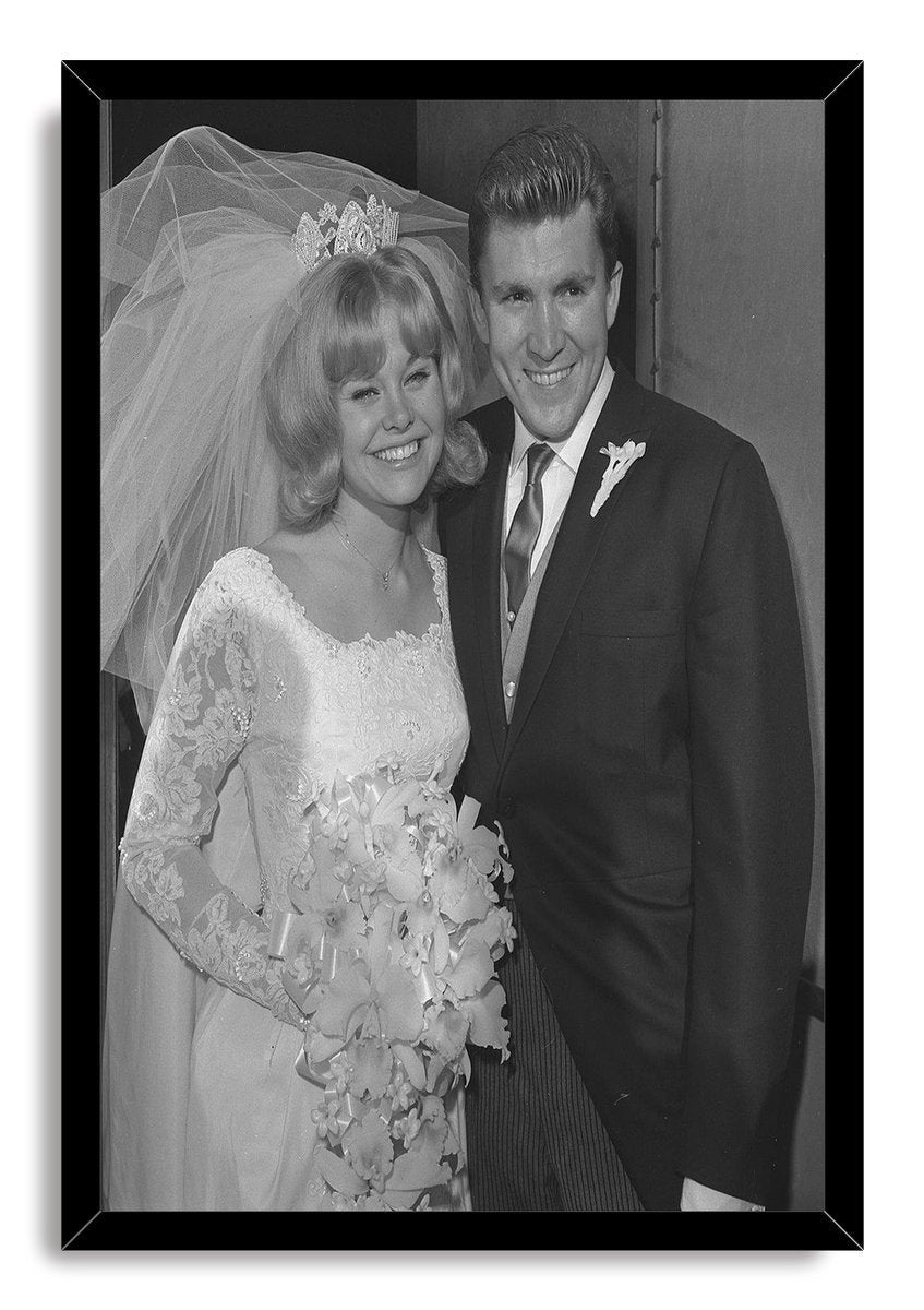 Kenny Lynch wedding wall art print in a black frame portrays the bride with veil and bouquet beside the suited groom.