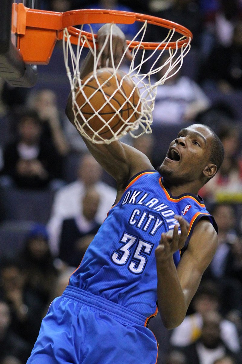 Kevin Durant poster captures the Oklahoma City number 35 player driving a basketball through an orange rim before a blurred crowd.