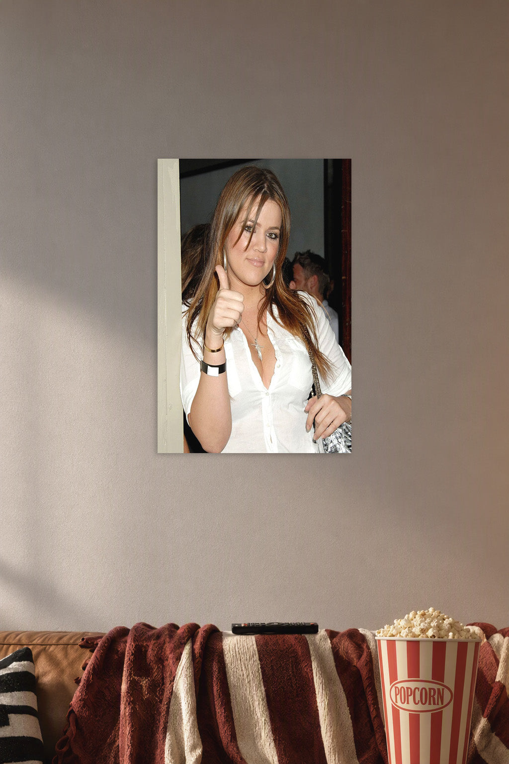 Khloé Kardashian in a cozy movie room above a brown sofa with popcorn.