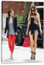 Kim and Khloé Kardashian canvas wall art print displaying the sisters walking outdoors beside a black SUV and carrying a red handbag.