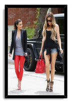Kim and Khloé Kardashian framed wall art print of the sisters walking by a black SUV, set in a sleek black border.